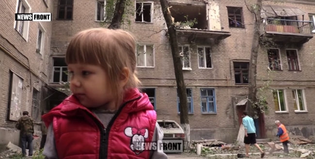Девочка в Донецке на фоне разбомбленного дома.